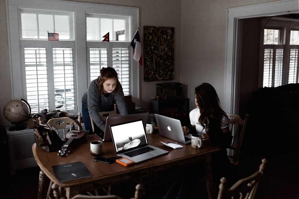 women using laptop on brown wooden table