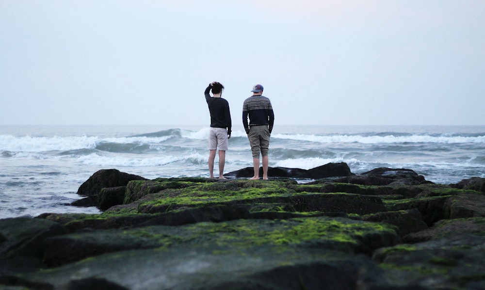 two men standing on cliff across the sea