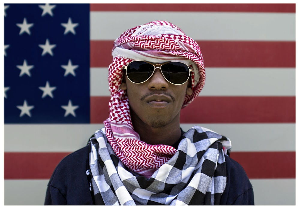 hombre con gafas de sol frente a la bandera estadounidense