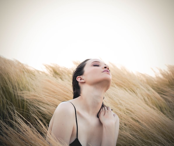 woman sitting along brown plants