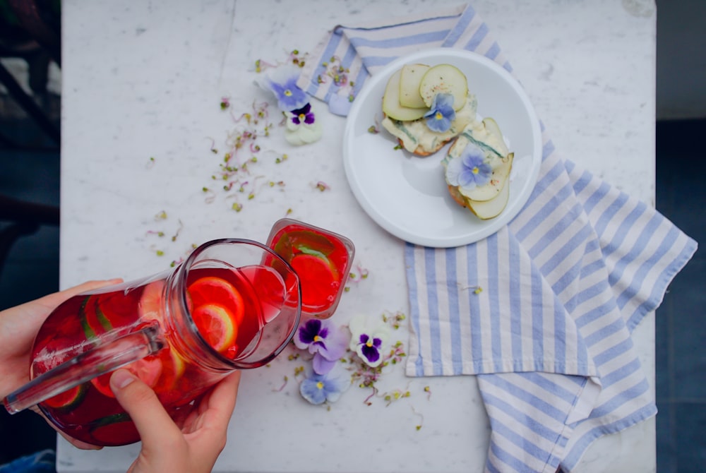 persona che riempie l'acqua con fette di limone al bicchiere