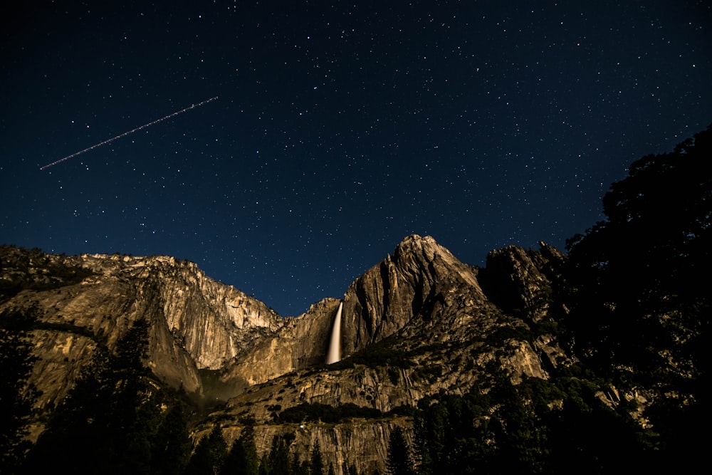 low angle photography of rock mountain under black sky at nighttime