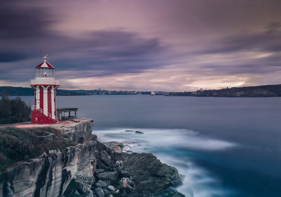 white and red lighthouse near body of water