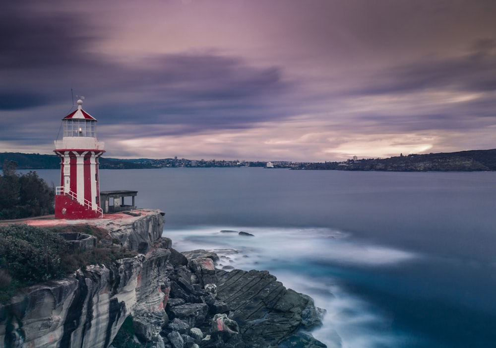 white and red lighthouse near body of water