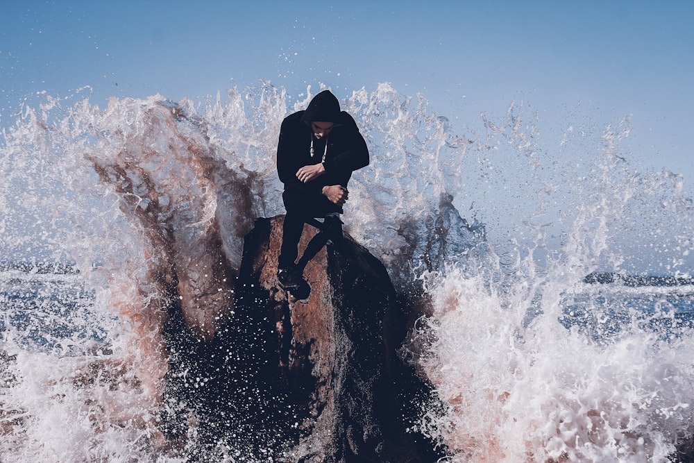 person in black jacket sitting on rock formation during daytime