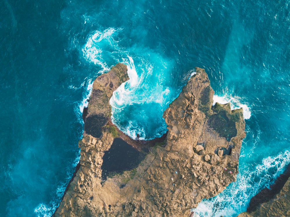 photo of brown rocks between blue body of water