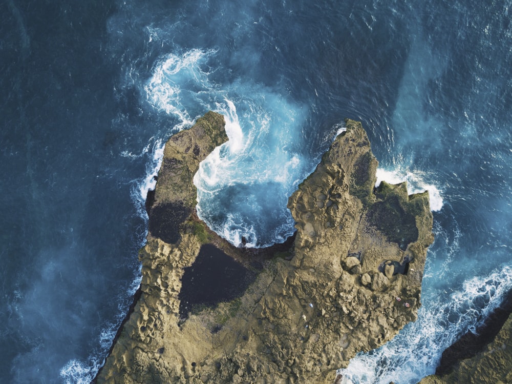 Photo de roches brunes entre un plan d’eau bleu
