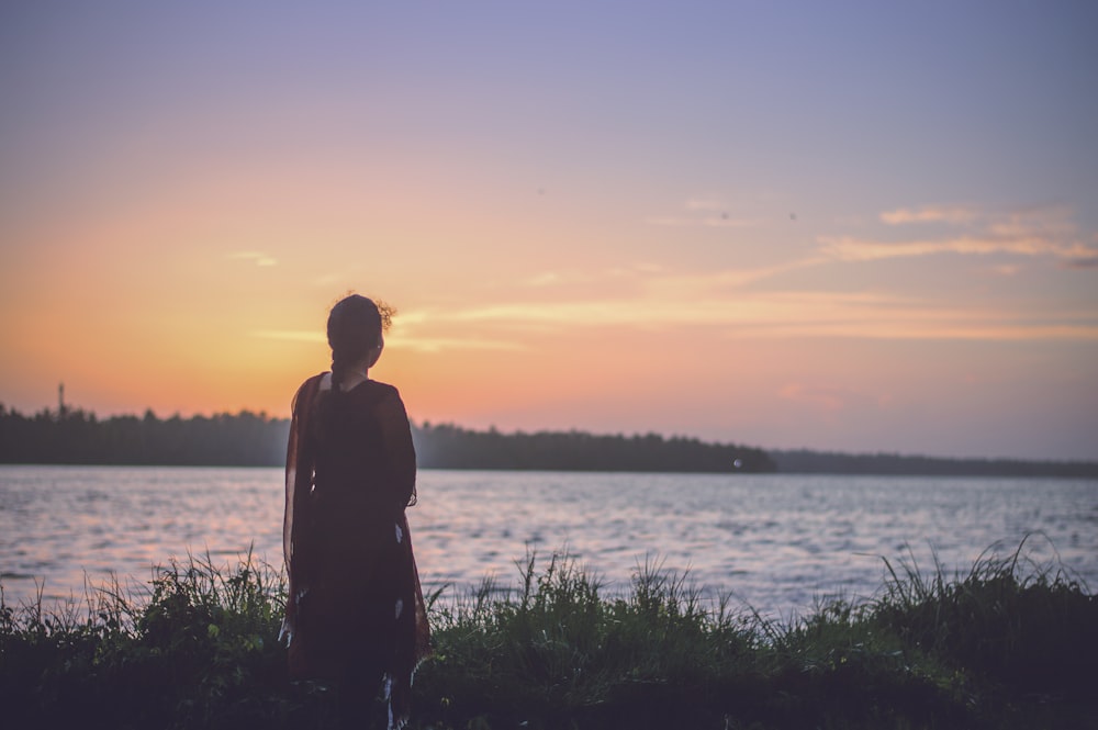 Silhouettenfotografie einer Frau, die auf ein Gewässer schaut
