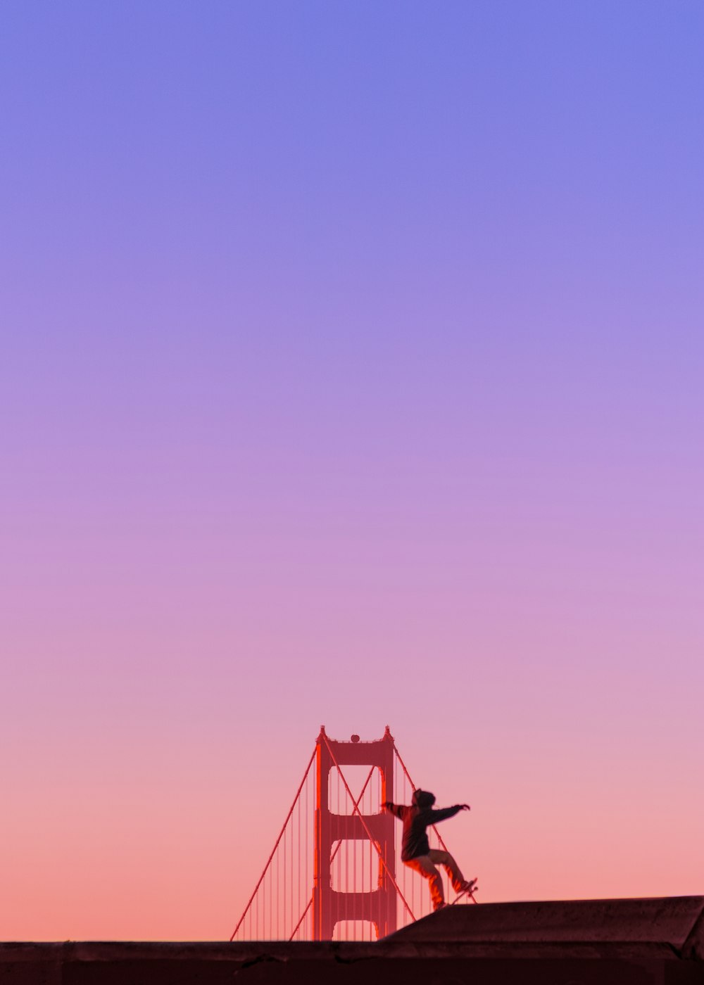 Mann fährt auf Skateboard vor der Golden Gate Bridge