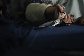 Workers carefully cutting fabric with precision tools in a clean industrial workshop.