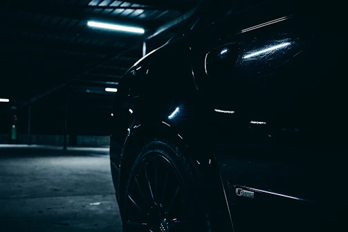 Side profile of a sleek classic coupe gleaming under soft garage lighting with gold accents.