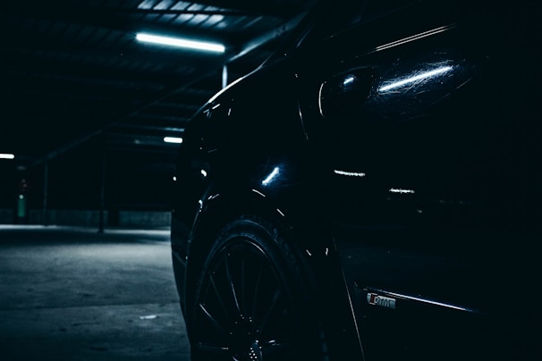 A classic black coupe gleaming under soft garage lighting, emphasizing its curves.