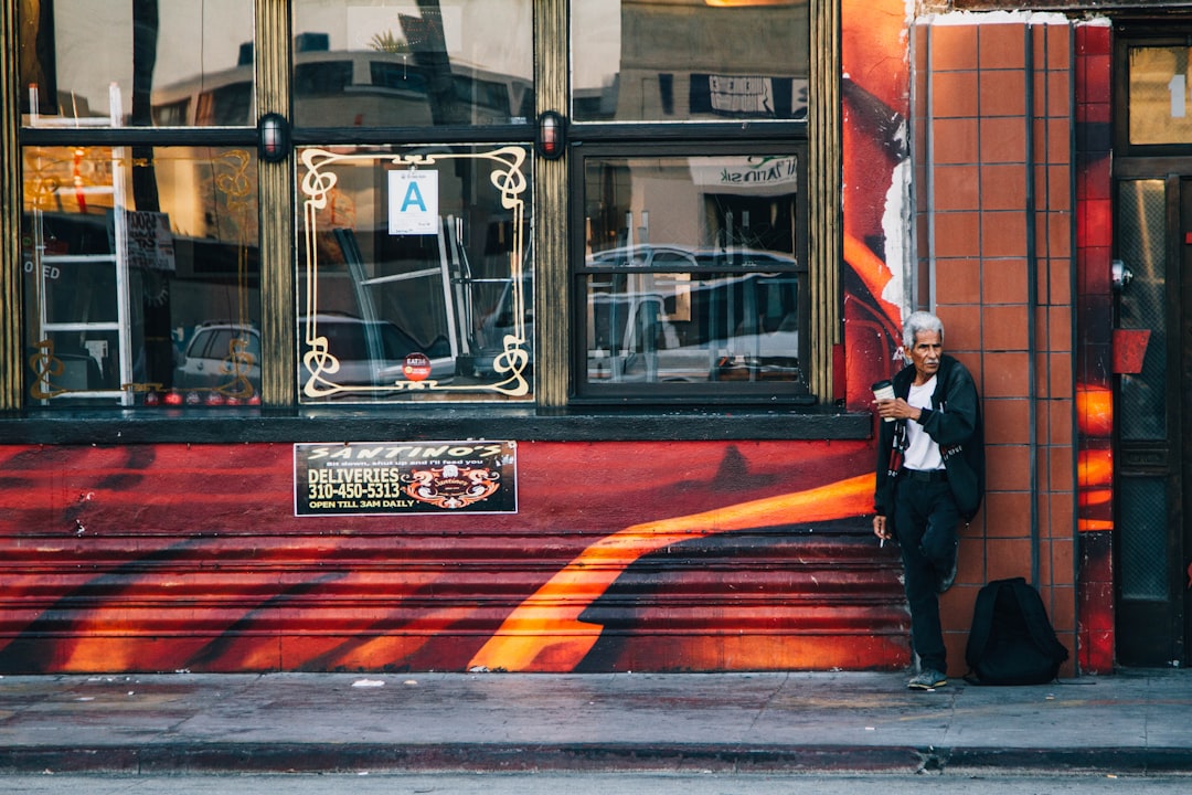 man leaning on brown and red painted wall