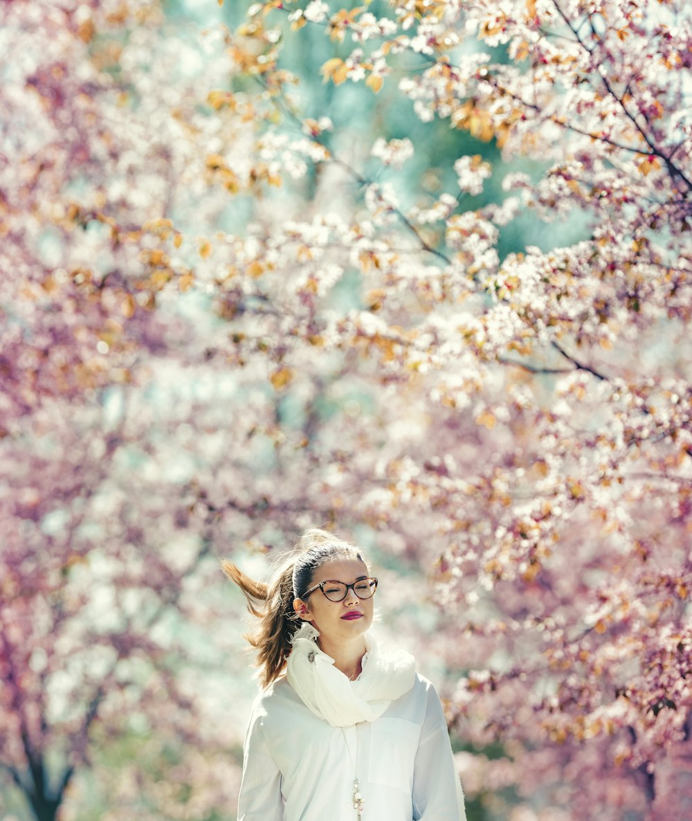Frau, die auf rosa Kirschbäumen steht, die einen Bereich umgeben