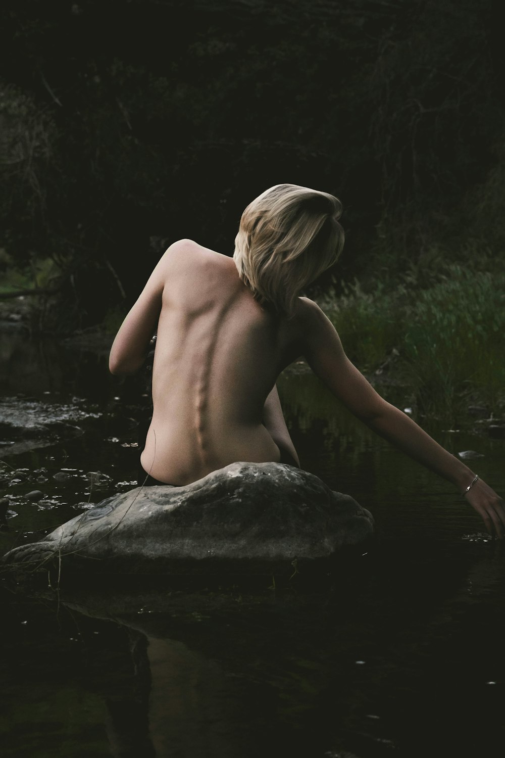 岩の上に座っている半裸の女性