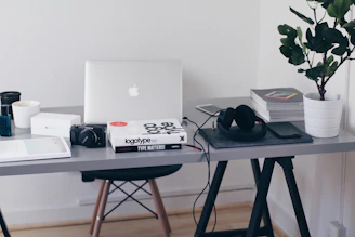 A minimalist workspace featuring a camera, laptop, and photography books.