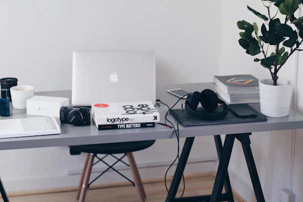 A minimalist workspace featuring a camera, laptop, and photography books.