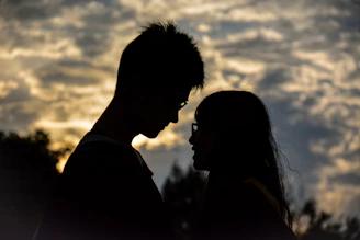 A shadowy silhouette of a couple entwined beneath a stormy sky.