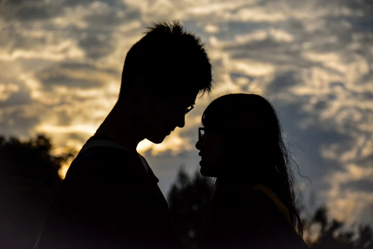 A shadowy silhouette of a couple entwined beneath a stormy sky.