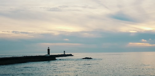 A serene watercolor scene of a lighthouse standing tall against a pastel sky.