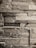 A textured wall made of rectangular stone slabs arranged in a staggered pattern. The stones vary in shade, creating a rustic and natural look.