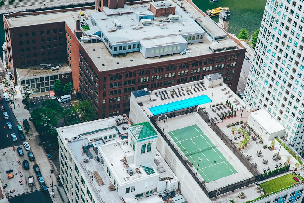 道路沿いの建物の上にあるテニスコートとプールの航空写真
