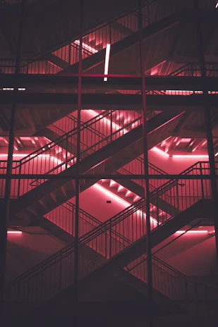 Futuristic digital staircase with glowing pink, tinto, and orange neon lights representing interactive game levels.