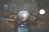A close-up of a shiny motorcycle helmet resting on a classic motorbike ready for rental.