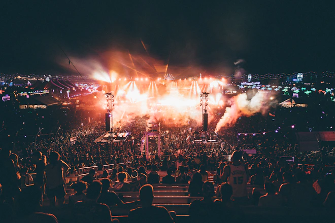 Crowd cheering under colorful stage lights at a lively outdoor rock festival.