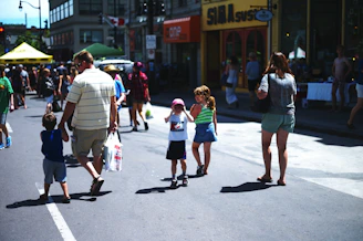 Children playing games and families browsing stalls at a lively community event.