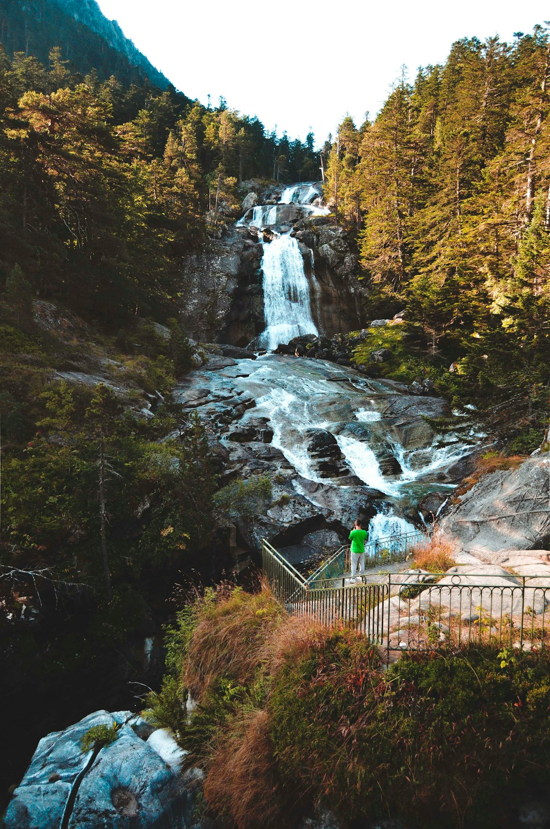 green metal fence near waterfalls during daytime