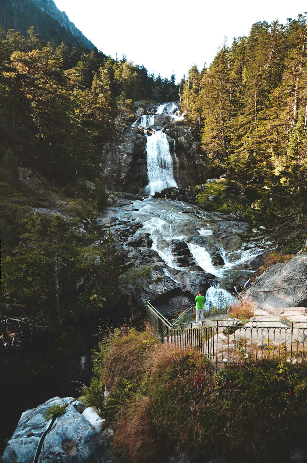 green metal fence near waterfalls during daytime