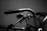 Close-up shot of a black leather riding glove gripping a motorcycle handlebar, with subtle matte black and white tones.