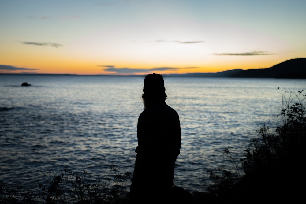 silhouette of person standing near water