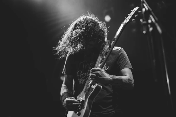 Black-and-white photo of Roberto Randazzo passionately playing guitar in a dimly lit Hamburg studio.
