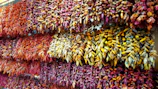 Dried long pepper (pipili) strands displayed on a natural fiber cloth.