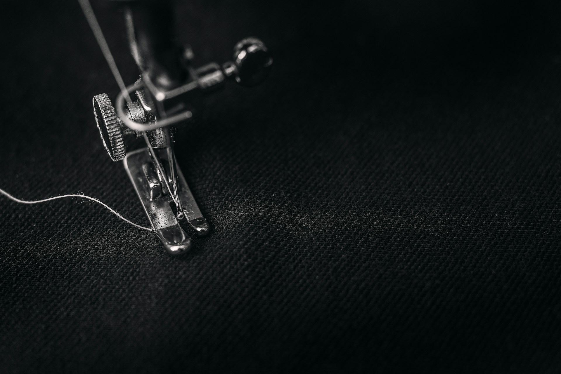 photo of gray sewing machine foot lock with thread on black cloth