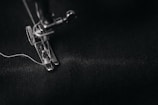 photo of gray sewing machine foot lock with thread on black cloth