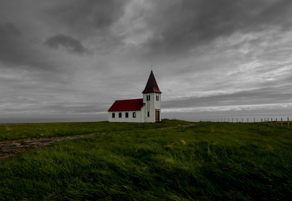 A white church building in the middle of farmland near the ocean, covered by gray clouds.