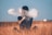 man sitting on brown grass field playing with smoke