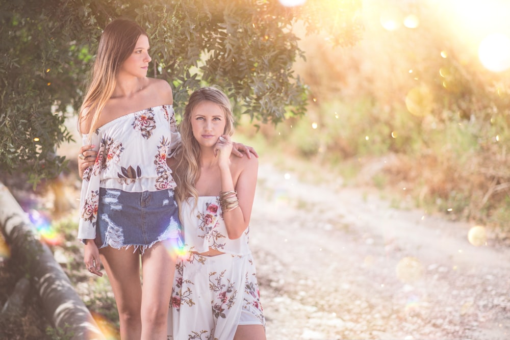 two women standing beside tree