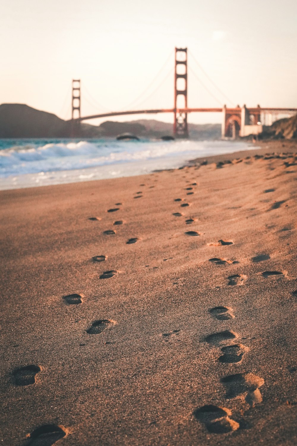 Footprints in the sand with the Golden Gate bridge in the background in San Francisco
