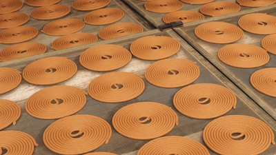Vibrant agarbatti sticks drying on racks in a sunlit room.