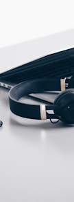 black cordless headphones beside closed black laptop computer and smartphone