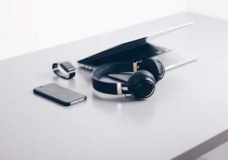 black cordless headphones beside closed black laptop computer and smartphone