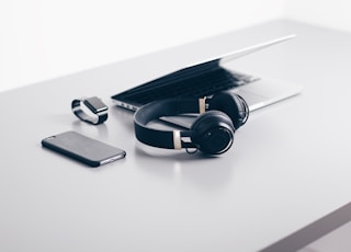 black cordless headphones beside closed black laptop computer and smartphone