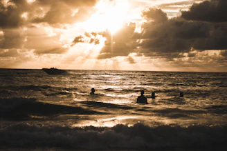 Safety boat and maritime team supporting swimmers near El Arco at sunrise.