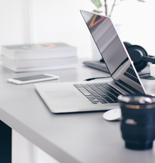 silver MacBook Pro on white table