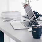 silver MacBook Pro on white table