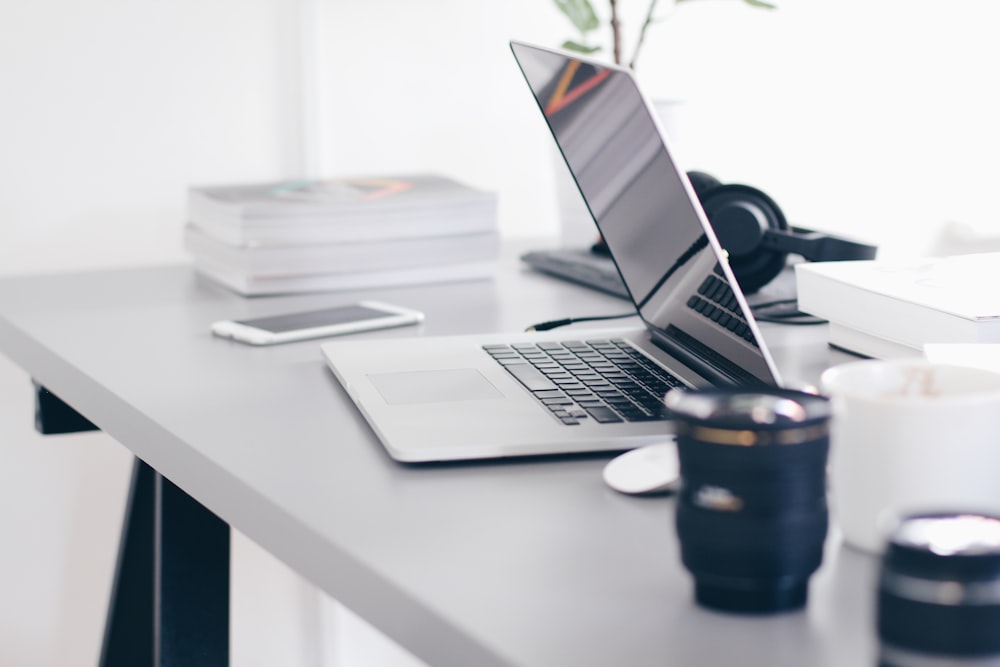 silver MacBook Pro on white table